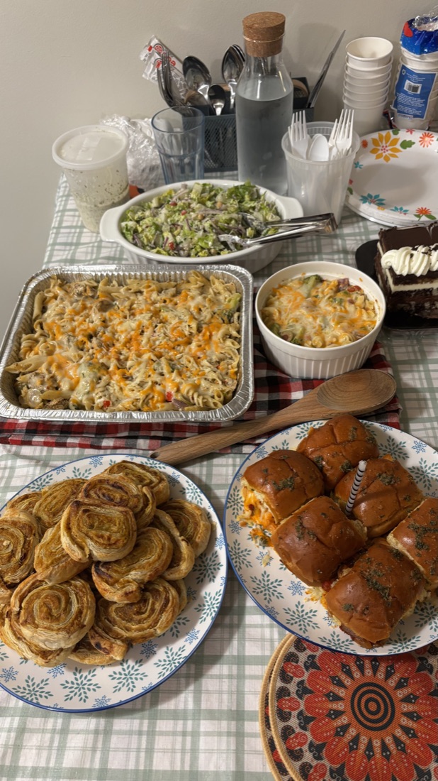 A home-cooked dinner spread of pasta bake, sliders, and pinwheel pastries